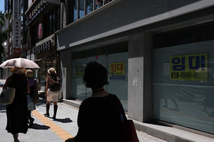 Pedestrians pass by a commercial building plastered with for-lease signs in Seoul, June 23. Yonhap