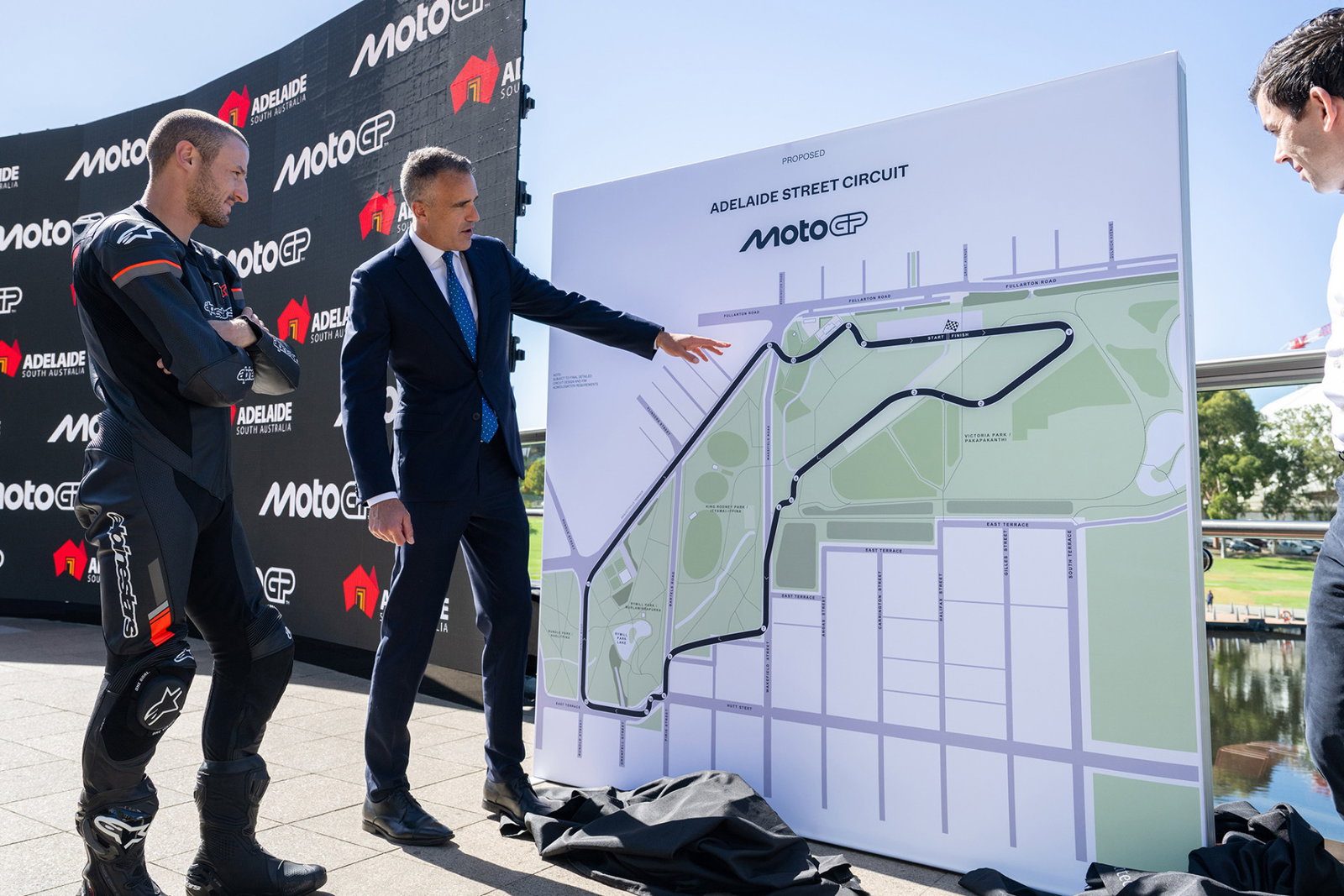 Pater Malinauskas, Jack Miller, and Carlos Ezpeleta inspect the plan for MotoGP at Adelaide.