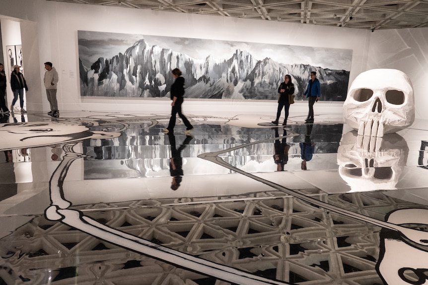 People walk around exhibits in an art gallery