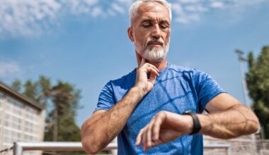Confident senior athlete after running at the sports stadium on a running track taking a break taking pulse