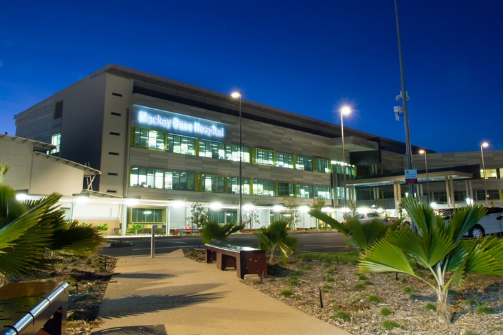 A multi-storey building with a neon sign that says "Mackay Base Hospital".
