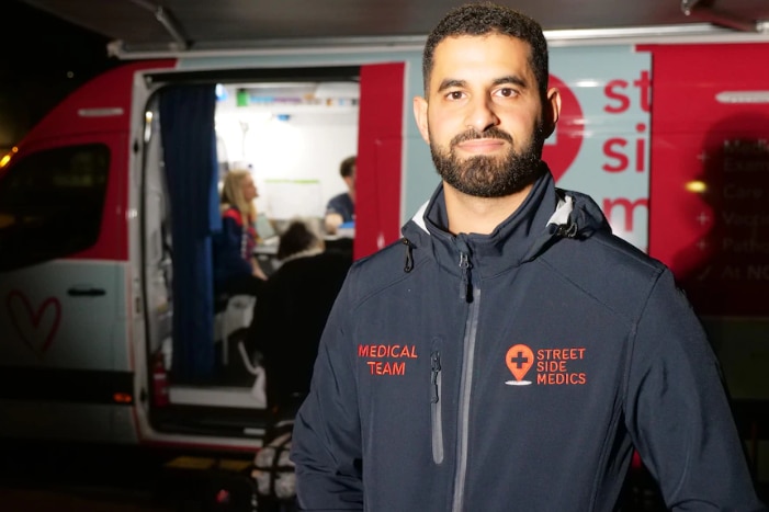 A man stands in front of a medical van.