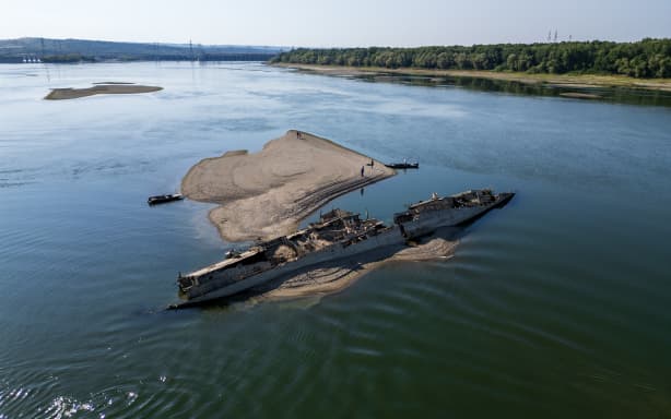This aerial photograph shows the wreckage of a World War II German warship, one of dozens sunk by retreating Nazi forces in September 1944, emerging from the low waters of the Danube River near Prahovo, Serbia, on August 11, 2026, as drought and prolonged hot and dry weather continues to lower water levels across the region. Heat and drought are driving rivers across Europe to record lows. Low levels along the Danube river have already seen Hungary and Romania forced to consider shuttering their nuclear plants, which rely on the water for cooling, in late July, though both managed to avoid doing so for now. (Photo by Andrej ISAKOVIC / AFP)