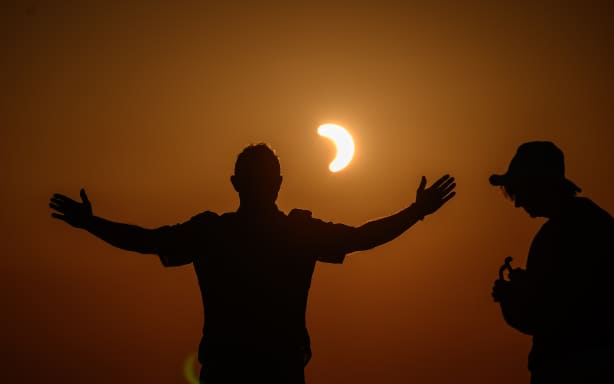 People watch a partial solar eclipse at the Chasseral peak, above Nods, northwestern Switzerland, on August 12, 2026. The eclipse was mainland Europe's first total eclipse since 2006. Throughout human history eclipses have stirred amazement, fear and reverence, as they appear to momentarily halt the normal course of nature, creating a strange twilight during which temperatures drop, shadows appear at strange angles and some animals go to sleep. (Photo by Fabrice COFFRINI / AFP)