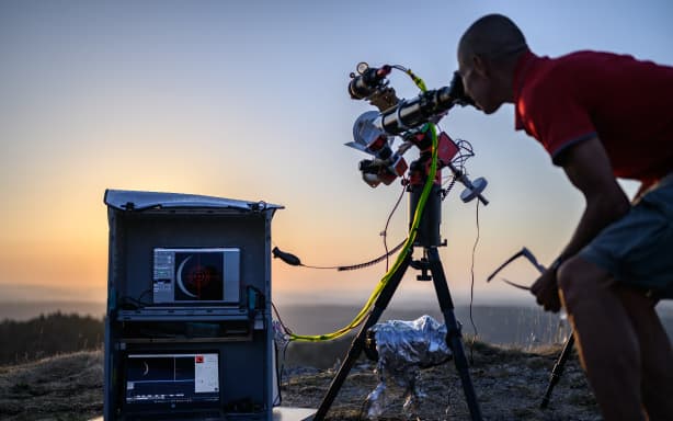 An astronomy enthusiast observes a partial solar eclipse at the Chasseral peak, above Nods, northwestern Switzerland, on August 12, 2026. The eclipse was mainland Europe's first total eclipse since 2006. Throughout human history eclipses have stirred amazement, fear and reverence, as they appear to momentarily halt the normal course of nature, creating a strange twilight during which temperatures drop, shadows appear at strange angles and some animals go to sleep. (Photo by Fabrice COFFRINI / AFP)