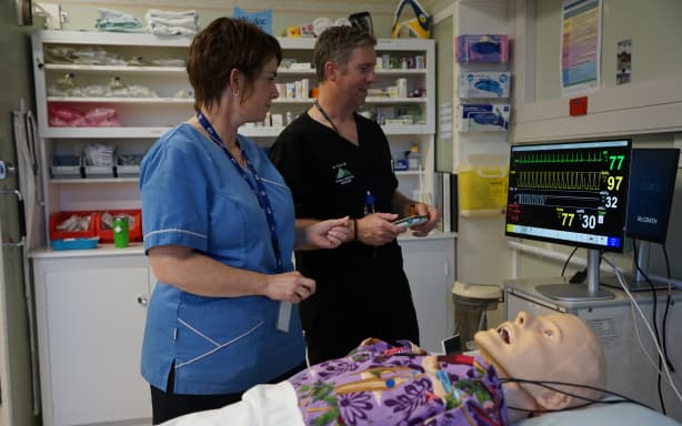Lecturers Chris Hill and Karly Burrowes study a simulation patient monitor.