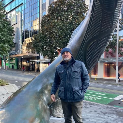 Artist Chris Bailey (Ngāti Hako, Ngāti Pāoa, Ngāti Porou, Te Aupōuri) with Horotiu, the seven-metre bronze sculpture depicting the legendary tuna kūwharuwharu (longfin eel).