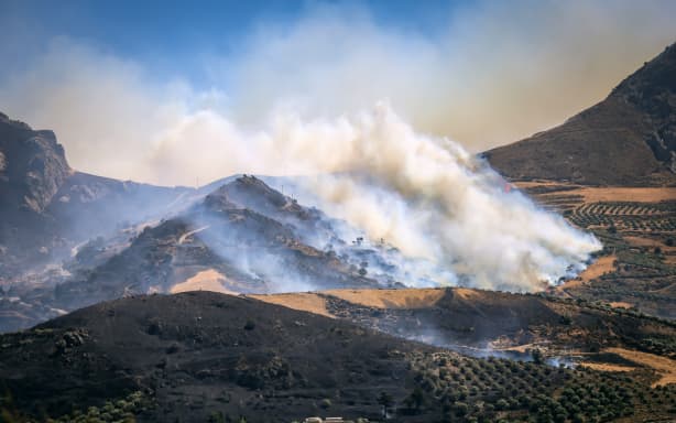 This photograph shows a burning area during a wildfire near the village of Asomatos in the Greek island of Crete on July 30, 2026. two firefighters died battling a forest blaze on the Greek island of Crete on Wednesday, the fire department said as several fires broke out around the country, fed by gale-force winds. The fire department in a statement said the men had died "during an operation to contain a rural forest fire in the Krya Vrysi area of Rethymno." (Photo by Costas Metaxakis / AFP)