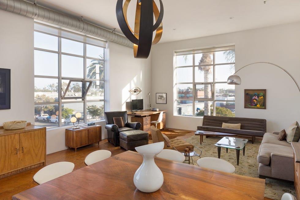 Stylish modern living space featuring large windows, wooden furniture, and a decorative light fixture.