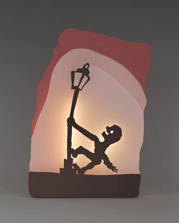 Silhouette of a person climbing a streetlamp with colorful background illumination.