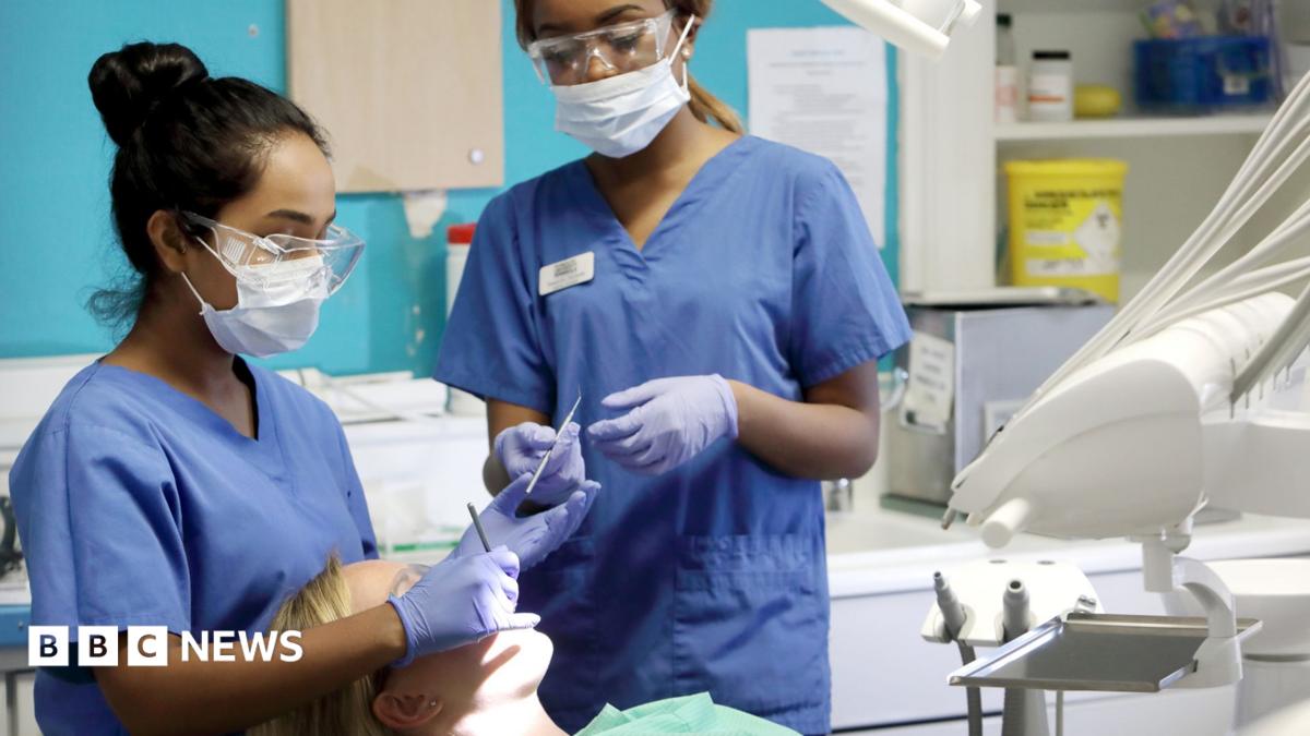 Young female dentist and assistant working on female patient in chair