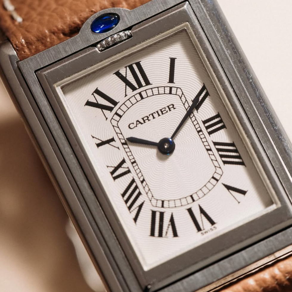 rectangular cartier watch with roman numerals and leather strap.