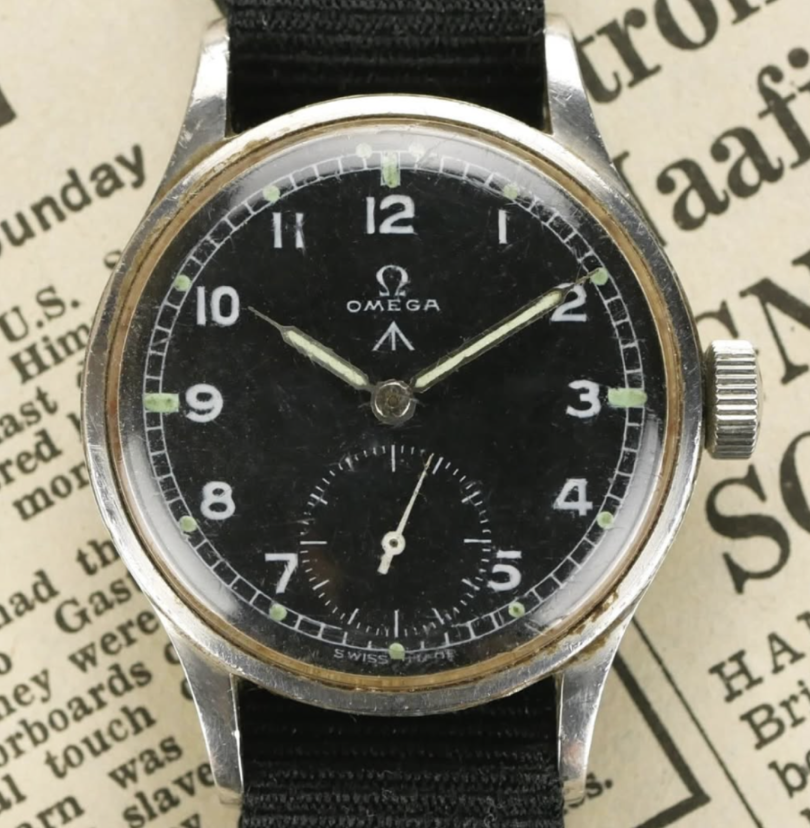 vintage omega military watch with black dial and arabic numerals on a newspaper background.