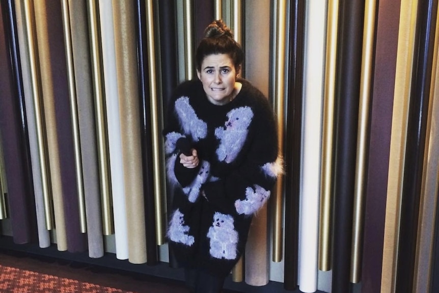 A woman wearing a knitted long cardigan with a black background with grey bears on it.