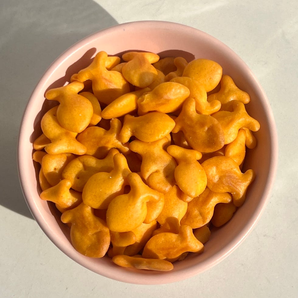 Bowl of goldfish-shaped snacks on a light colored surface with a shadow. Bowl of goldfish-shaped snacks on a light colored surface with a shadow.