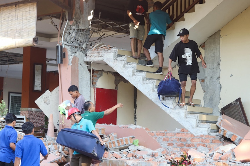 People are moving luggages from a destoreyd stairs and rubbles
