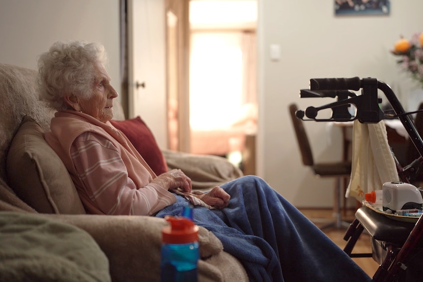 Audrey Staniland sits on a couch, pictured from side-on.