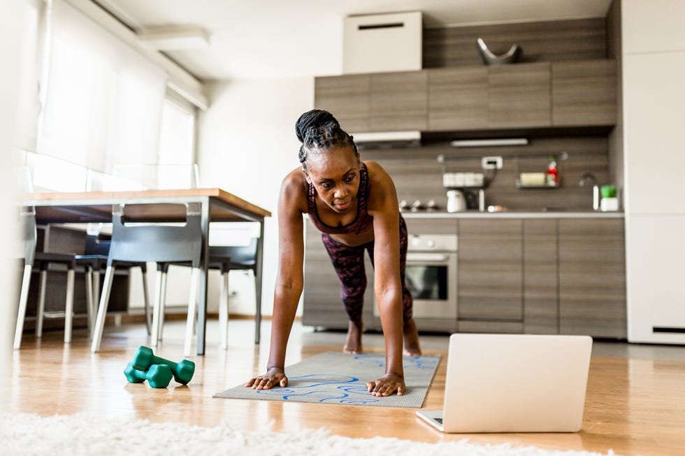 best exercise routine for stronger bones: woman doing press ups while looking at a laptop in a kitchen