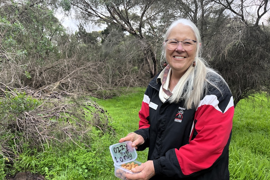 A woman holds a lunch box that says Ozzy one treat only