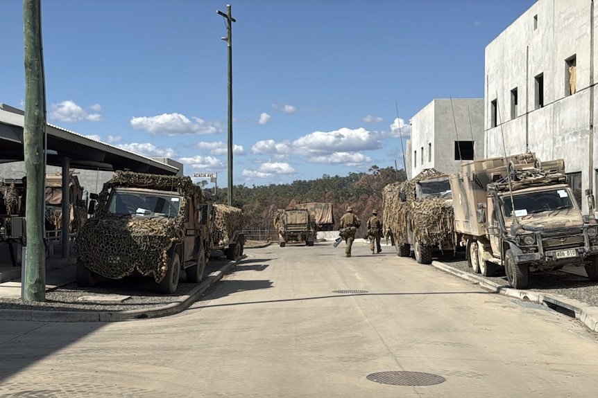 Army vehicles parked on a street with grey buildings