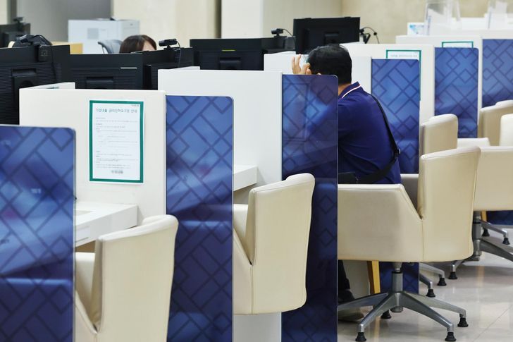 A customer speaks with a bank official in Seoul, Aug. 5. Yonhap