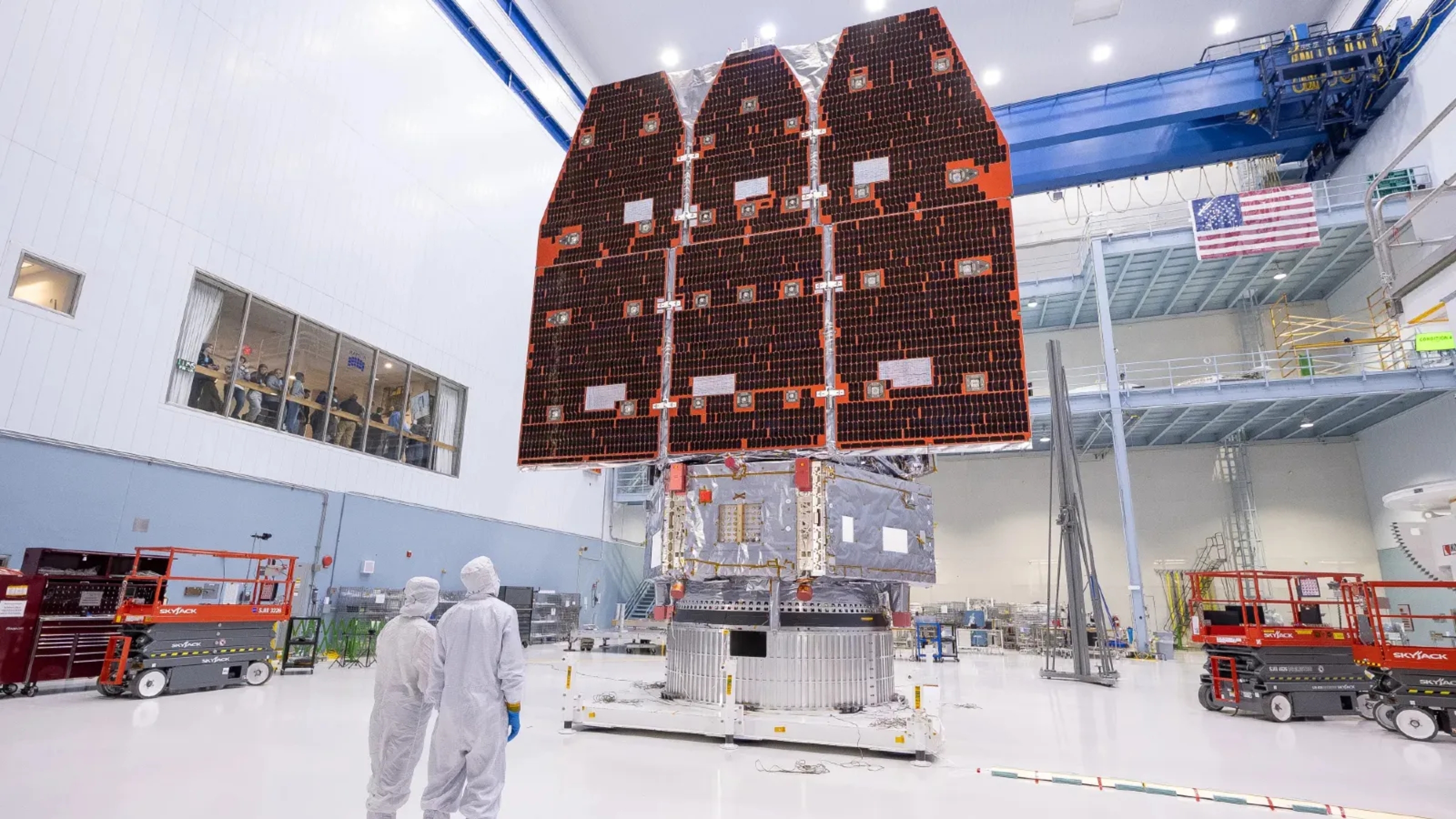 A photo of scientists stood next to the fully completed Roman telescope in a clean room