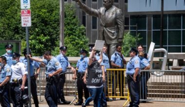 A protester walks near the Frank Rizzo statue as Philadelphia police guards the area during a protest in 2020.