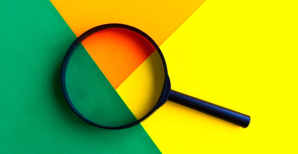 A black magnifying glass over the connection of geometric green, orange and yellow shapes to illustrate the finding that distinct lung endotypes in severe pneumonia highlight potential targets for personalised therapy