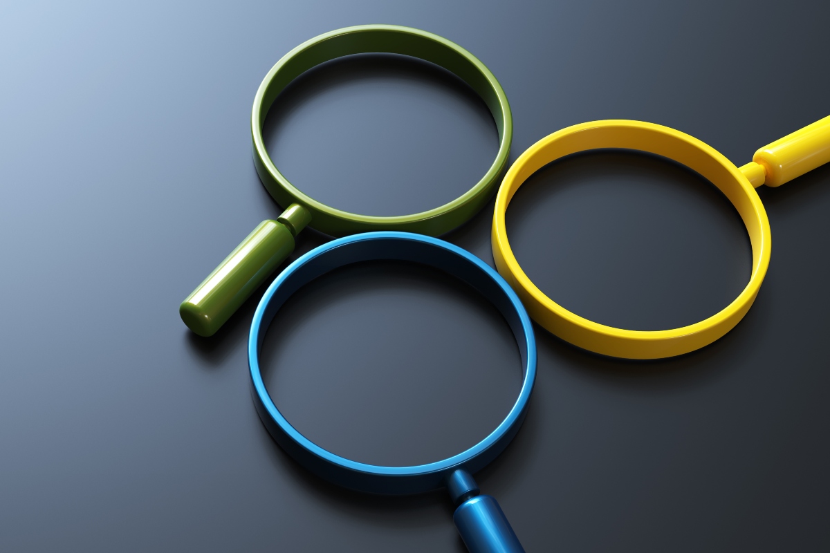 Three magnifying glasses in gree, yellow and blue laying on a dark grey background to illustrate the fact that distinct pulmonary inflammatory endotypes have been identified in suspected severe pneumonia