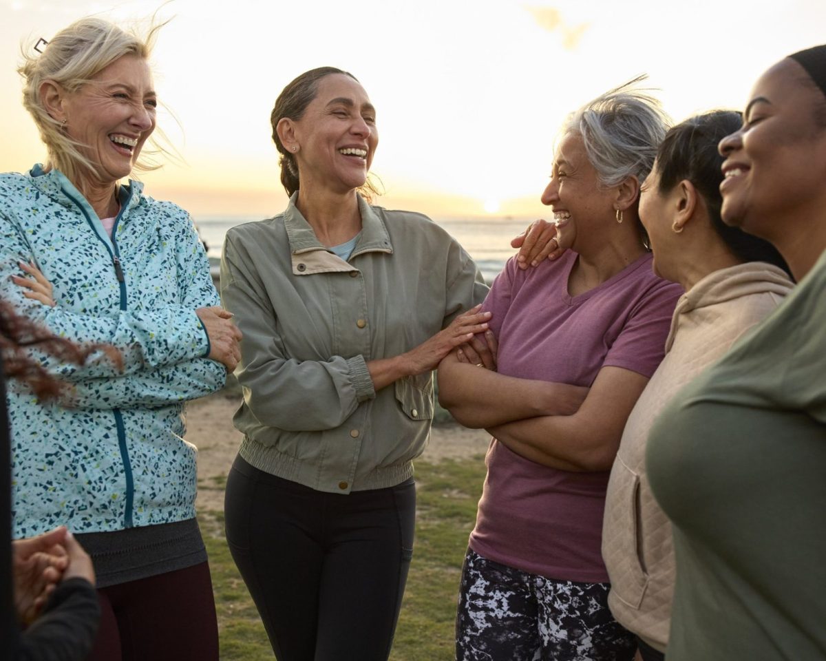 Happy woman spending leisure time with friends at sunny day. Multiracial females are talking with each other. They are wearing sports clothing.