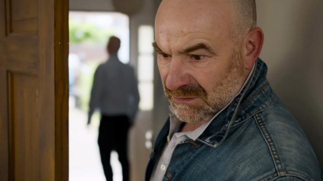 Tim looks into a room with Richie in the background in Corrie. Tim looks horrified