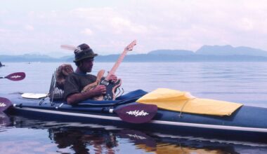 Jim Nollman playing electric guitar in a modified kayak.