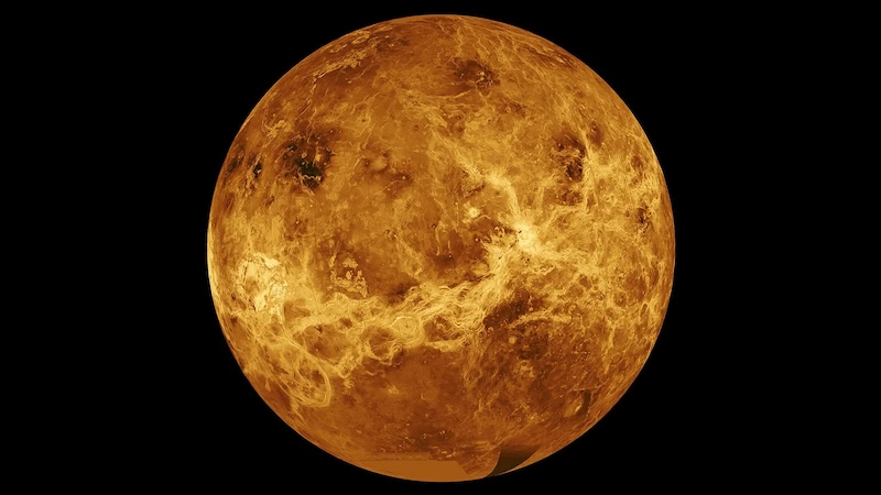 Bright, orange and yellow mottled planet with varied surface texture, on black background.