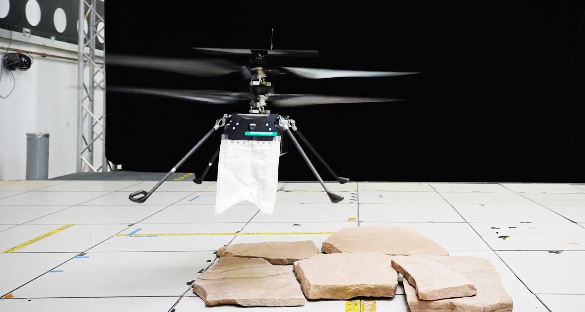 A tiny helicopter drone has a small white cape.