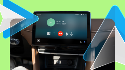 A car dashboard display running Android Auto during a phone call, with the Android Auto logo overlaying.