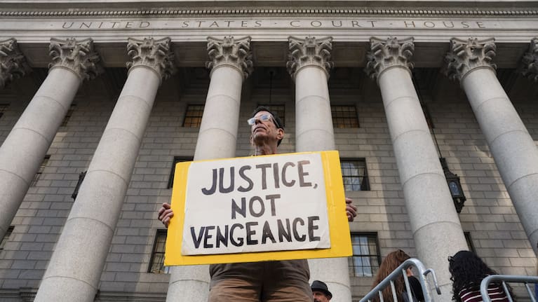 A man holds a sign outside of Manhattan Federal Court on the day of a hearing for Luigi Mangione