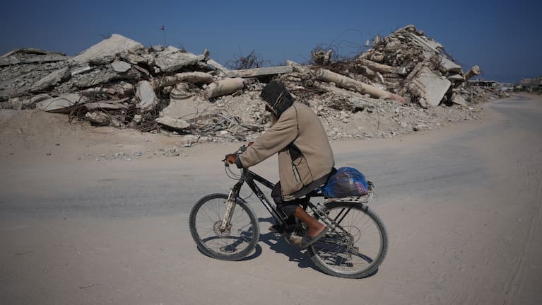 A Palestinian man rides his bicycle by the rubble of buildings that were destroyed during the Israel Hamas war, in Khan Younis, southern Gaza Strip, Friday, July 31, 2026.