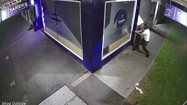 A person trying, and failing, to smash a window at Tareks Barbershop.