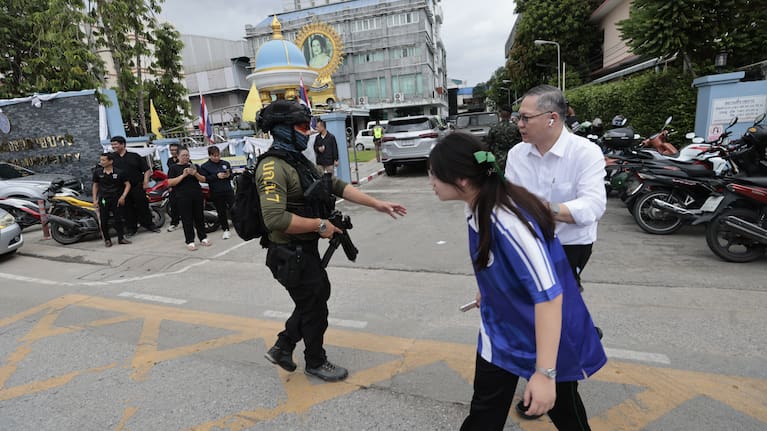A schoolgirl walks past a policeman standing guard after a shooting at the Debsirin Nonthaburi School in Thailand's Nonthaburi province, Friday, August 7, 2026.