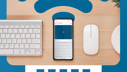 A smartphone displaying the Bluetooth Keyboard & Mouse app interface, placed between a physical white keyboard and mouse on a wooden desk.