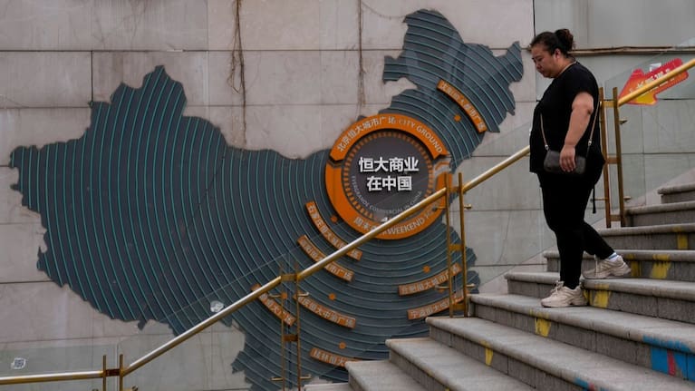 A woman walks by a map showing Evergrande development projects in China, as she heads to an Evergrande city plaza in Beijing on September 18, 2023.