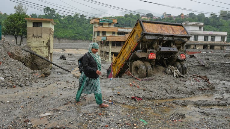 A woman walks through mud and debris left behind by flash flooding in Nepal's Nuwakot district, Saturday, August 29, 2026. 