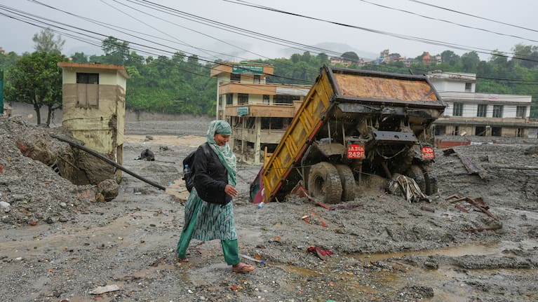 A woman walks through mud and debris left behind by flash flooding in Nepal's Nuwakot district, Saturday, Aug. 29, 2026.