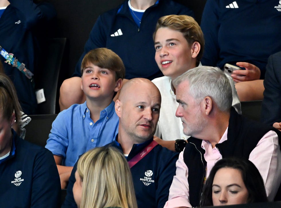 Children and adults engaged in conversation, with some looking towards the front, in a crowd setting.