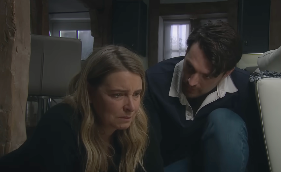 two people sitting on the floor, one looking serious, the other comforting. two people sitting on the floor, one looking serious, the other comforting.