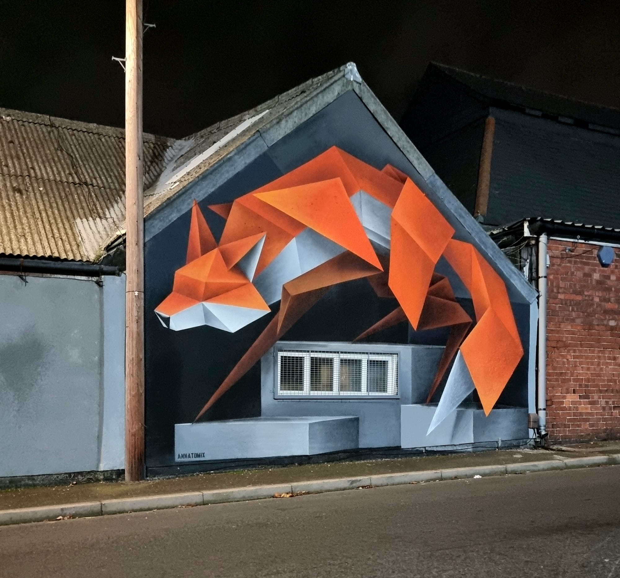a geometric fox mural by Annatomix on the side of a building at night