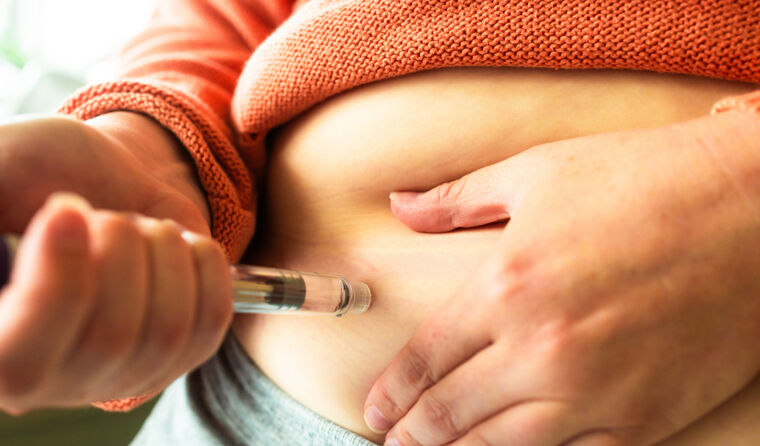 A person injecting a weight loss drug into belly.