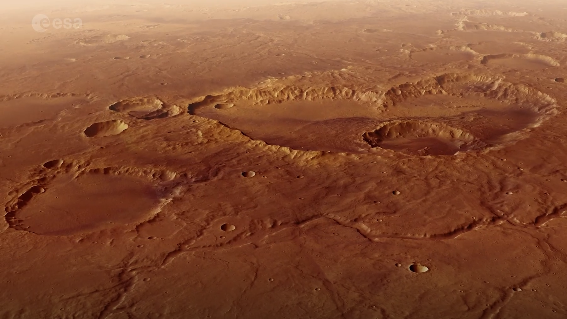 a rusty red landscape shows a smattering of craters from a high altitude.