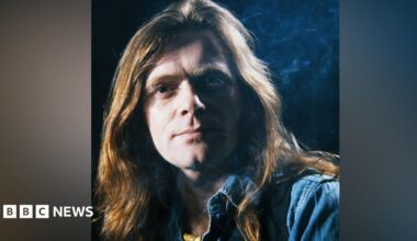Guitarist Henry McCullough pictured in 1979. he has long light brown hair and is wearing a blue shirt