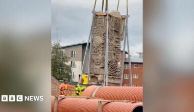 A close-up of the Aztec-style mural being lifted up by metal cranes.